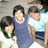 Three people in casual clothing pose together with arms around each other against a light background.