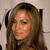 A static pixelated image of a person with long brown hair wearing a dark top against a light background.