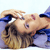 A pixelated image shows a person with light brown hair lying on their back, wearing a blue top, with one arm raised near their head.