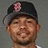 Pixelated portrait of a person wearing a dark cap with a pink floral emblem, neutral expression, and light-colored shirt against a gray background.