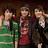 Five people in casual clothing stand side-by-side with a red pixelated text overlay on the right, set against a dark brown background.