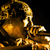 Pixelated static image of a golden-yellow figure with flowing hair against black background, rendered in low-resolution 256x256 pixels with visible dithering and blocky artifacts.