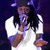 Pixelated image of a person with dark hair wearing a white shirt, holding a white object in each hand against a dark background.