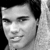 Black-and-white pixelated portrait of a person with short dark hair, neutral expression, and visible ear, cropped to show head and upper neck against dark background.