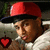 Pixelated image of a person wearing red and black cap, brown hair, white shirt with visible collar, holding small red heart-shaped object.