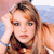 Static pixelated image of a person with light brown hair and fair skin, wearing dark clothing against a blurred background with pink and blue tones.