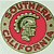 Circular pixelated icon with green and red patterned border, central red crescent shape, and pixelated face in green tones.
