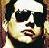 Pixelated close-up of a person wearing dark sunglasses and light-colored hair, with visible facial features including lips and nose.