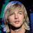 Pixelated close-up of a person with light brown hair, closed eyes, and a black choker against dark background.
