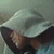 A hooded figure with a light blue garment and dark inner layer, head bowed in multiple showing text overlays