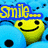 Pixelated yellow smiley faces with black eyes and mouths float on a blue background with scattered black dots, surrounded by fragmented text in yellow and blue.
