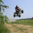 A pixelated image shows a person riding an ATV on a dirt path with greenery and blue sky, next to red displaying text