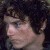 Pixelated close-up of a person's face with dark hair and light skin, showing partial facial features against a dark background.