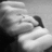 Black-and-white image of a person's face with hands near the mouth, transitioning to include text overlay.