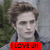 Pixelated image of a person with light brown hair wearing dark clothing, overlaid by red text reading 'I LOVE U!' on a gray and green background.