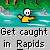 Pixelated character with white skull face and yellow shirt floats in turquoise water with green forest background, text reads 'Get caught in Rapids' below.