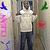 Pixelated static image of a person in light-colored shirt and dark pants standing against textured background with scattered colored shapes.