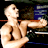 Static pixelated image of a shirtless male figure with light skin tone extending his arm toward the right side, set against dark background elements including blue and brown shapes.