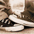 Animated sequence showing a character's feet in white sneakers with black laces, transitioning from a neutral stance to a pink-shoed pose on a dark background.