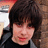 A pixelated image shows a person with dark hair and a black top against a blurred background, with blue text reading "Would You Like To Poke My Belly?" on a solid blue field.