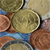 A pixelated close-up of a round, light brown object with a smooth surface, partially framed by darker brown curved shapes and a blue horizontal band below.