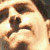 A pixelated close-up of a person's face with light skin tone, dark hair, and visible eyes, nose, and mouth against a bright background.