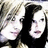 Two pixelated faces with light skin tones and dark hair, positioned side-by-side against a blurred background.