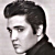Black-and-white pixelated static image of a person's head and shoulders with styled hair, visible facial features including eyes, nose, mouth, and ear, against a light gray background.