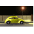 Yellow car drives left to right across dark street with glowing streetlamp and blurred background.