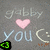 Pixelated icon with gray background showing 'gabby' text, pink heart symbol, and 'you :)' phrase above a colored triangular shape.