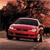 A red sedan with a dark roof is centered in a pixelated image, set against a blurred background of brown and orange tones.