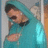 Pixelated image of a person with dark hair wearing a teal shirt, holding a glowing cyan object against a muted background.