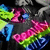 Pixelated image with vibrant pink, green, blue, and purple shapes against a dark background; no discernible text or figures.