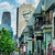 Pixelated cityscape with tall buildings, green trees, and a light blue sky with white clouds.