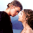 Pixelated static image of two people in a close embrace with one person kissing the other's cheek, wearing blue and dark clothing against a light background.