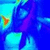 Pixelated abstract composition with dominant blue and cyan hues, featuring a small orange triangular shape on the left and a vertical purple streak across the center.