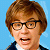 Pixelated close-up of a person with brown hair and glasses against a light blue background, wearing a dark jacket over a white shirt.