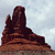 Pixelated brown rock formation with layered tiers against a light blue sky background.
