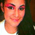 Pixelated close-up of a person's face with light skin, dark hair, and pink eyeshadow, wearing a white top against a dark background.