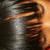 A pixelated static image shows a figure with brown hair and dark clothing against a gradient background transitioning from gray to orange.