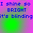 Blue pixelated text reads "I shine so I shine so BRIGHT it's blindingit's blinding" on a pink and green gradient background with subtle circular light effects.