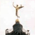 Pixelated figure with outstretched arms atop a dark, rounded base against a light background.