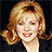 Pixelated portrait of a smiling person with light brown hair styled in waves, wearing red lipstick and dark clothing against black background.