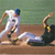 Two figures in athletic poses on a brown surface against a green background, one in white with blue accents, the other in dark clothing with yellow details.