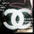 Pixelated static icon with white central shape containing dark green stylized letters 'J' and 'E', set against a blurred background of dark purple, black, and light brown tones.
