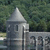 A pixelated image of a gray stone building with a pointed roof and columns, set against a green background.