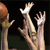 Pixelated image of multiple hands reaching upward against a dark background with a faint green lower section.