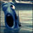 Pixelated blue whale with wide-open mouth and one visible eye, set against a striped background with text reading "WOW i wish i could speak" and "whale".