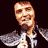 Pixelated static image of a person with light brown hair and facial features wearing a white shirt under a dark jacket, set against a solid black background.