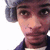 Pixelated close-up of a person wearing a dark blue cap and dark blue jacket with a white collar, set against a plain white background.